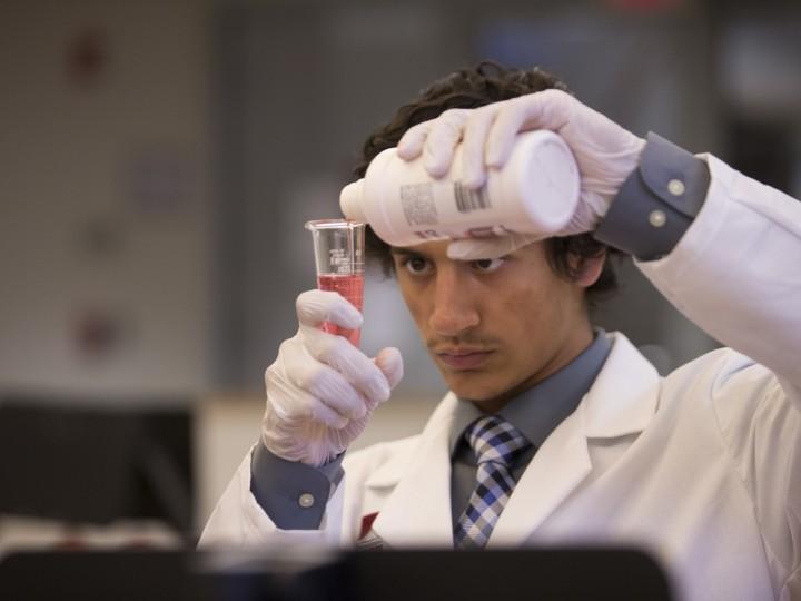 A student measuring wet compound ingredient with graduated cylindar